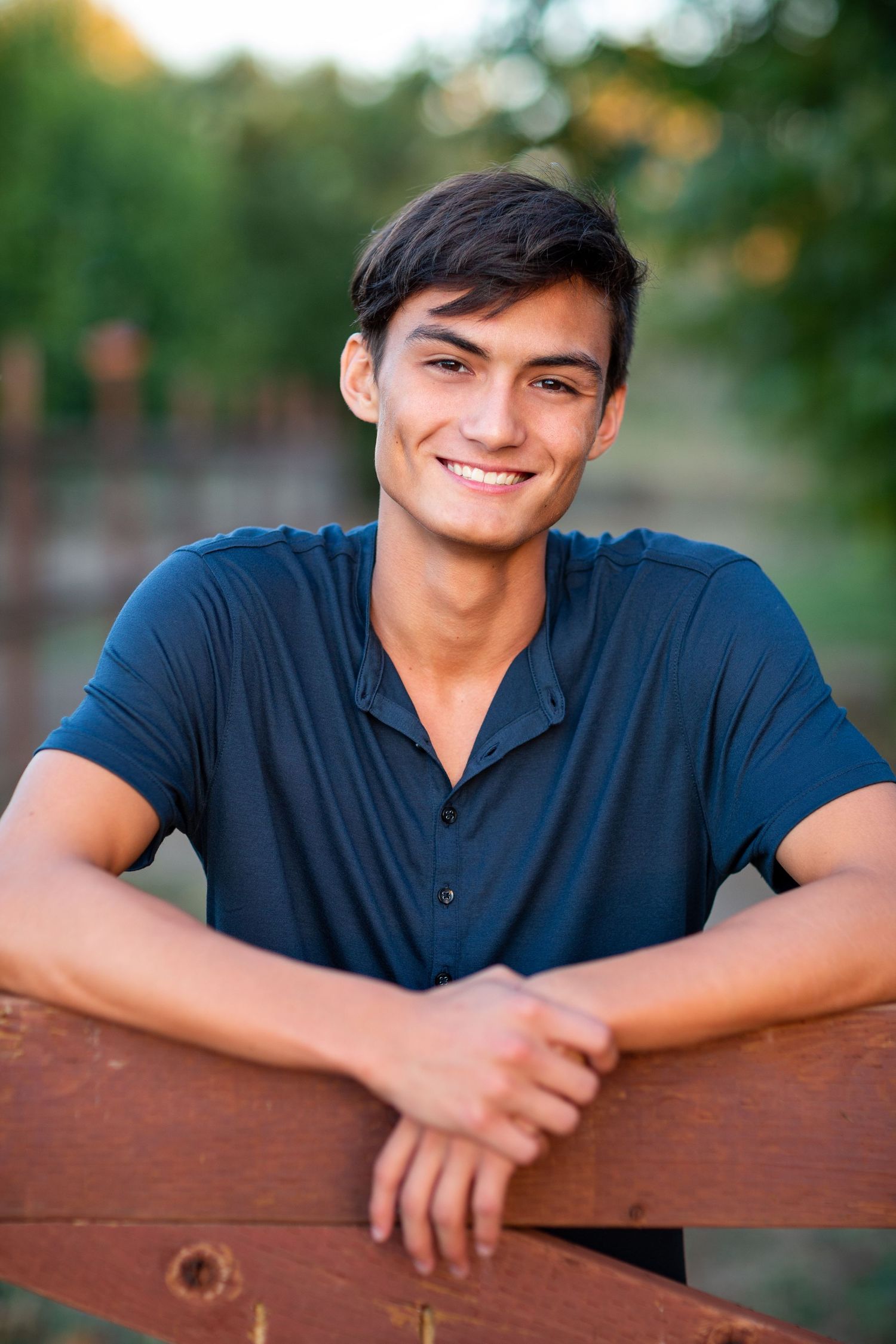 A casual portrait against a blurred outdoor background in natural lighting.