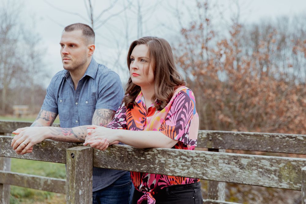 Couple sitting together on a rustic wooden fence during an outdoor photo session.