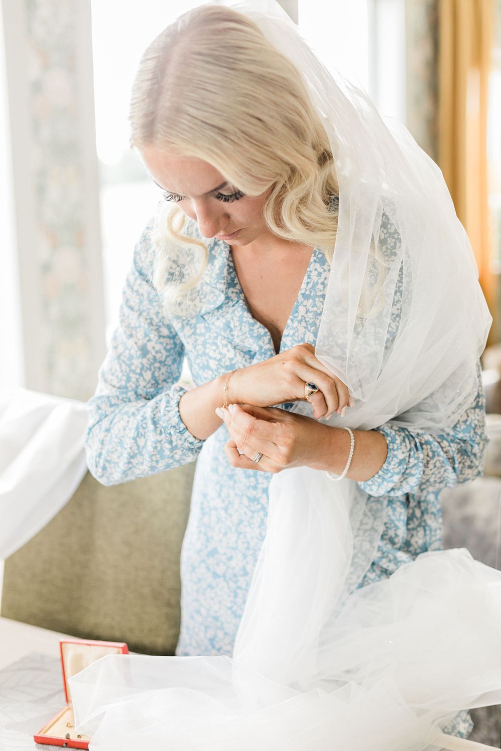 A person wearing a blue floral dress examines details while seated in morning light.