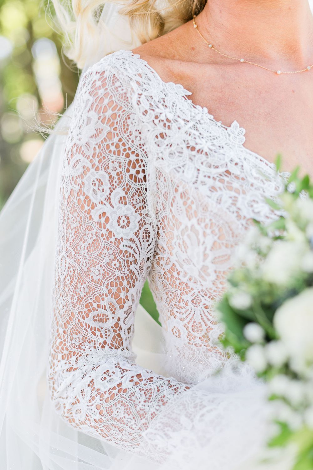 Detailed shot of delicate lace sleeve on wedding dress with floral pattern.