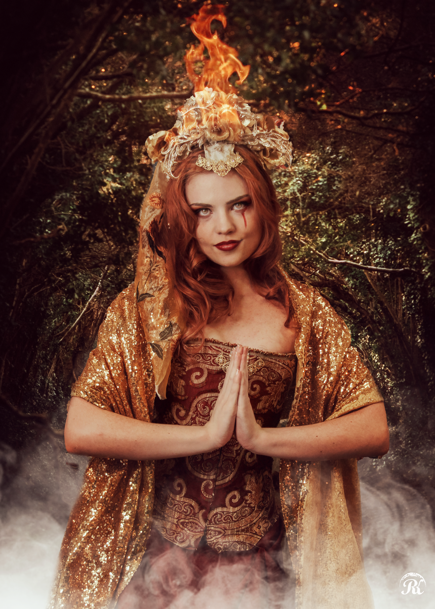Woman in golden robe with flaming crown performing mystical pose amidst magical fog.