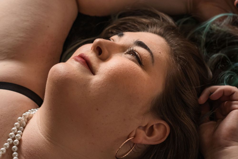 Close up artistic portrait showing dreamy expression in dramatic lighting with pearl necklace details.