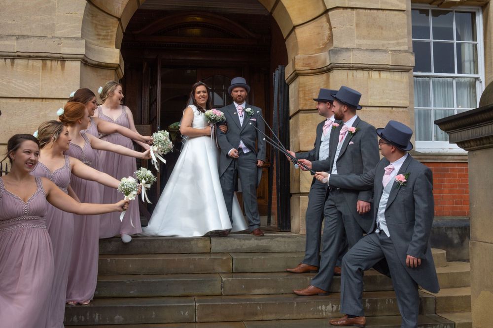 Wedding party gathered on historic building steps with bridesmaids in purple dresses.