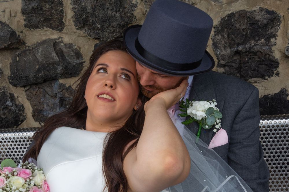 Romantic wedding portrait against a stone wall with flowers and vintage styling.