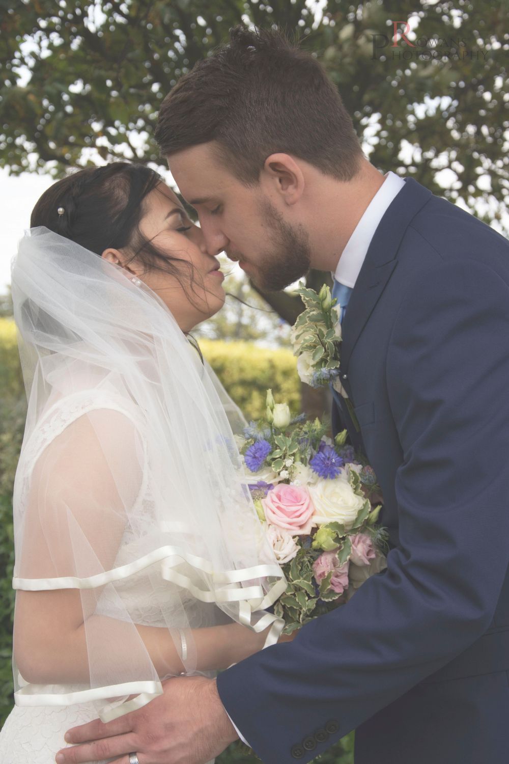 Intimate wedding portrait with soft focus and delicate floral bouquet.