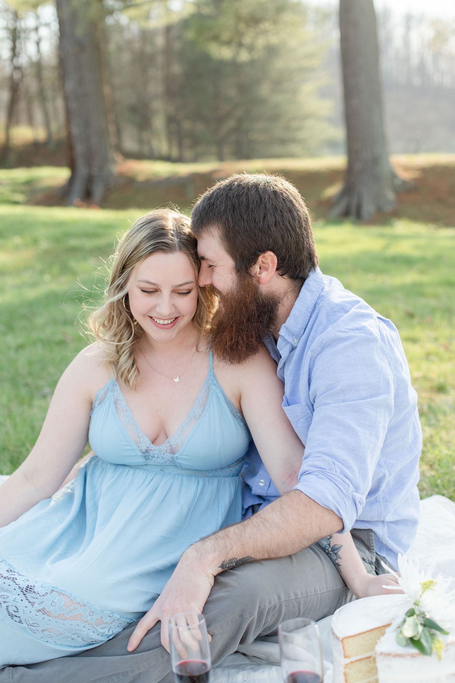 A couple in coordinating blue and grey outfits shares tender moments during an outdoor photoshoot.