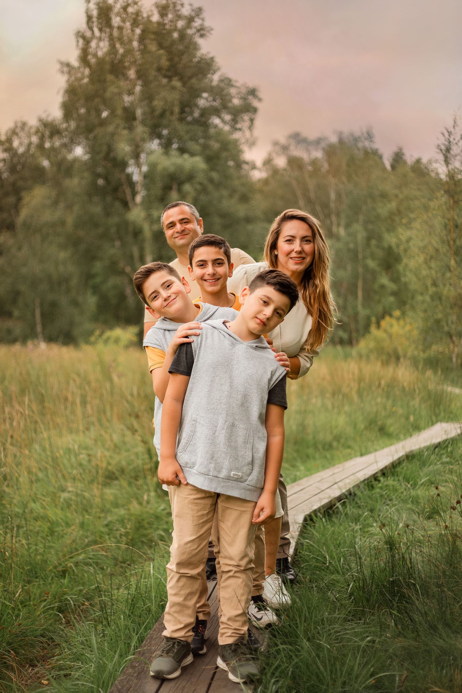 Familjefotografering. Mamma, pappa och barn står på en liten bro.