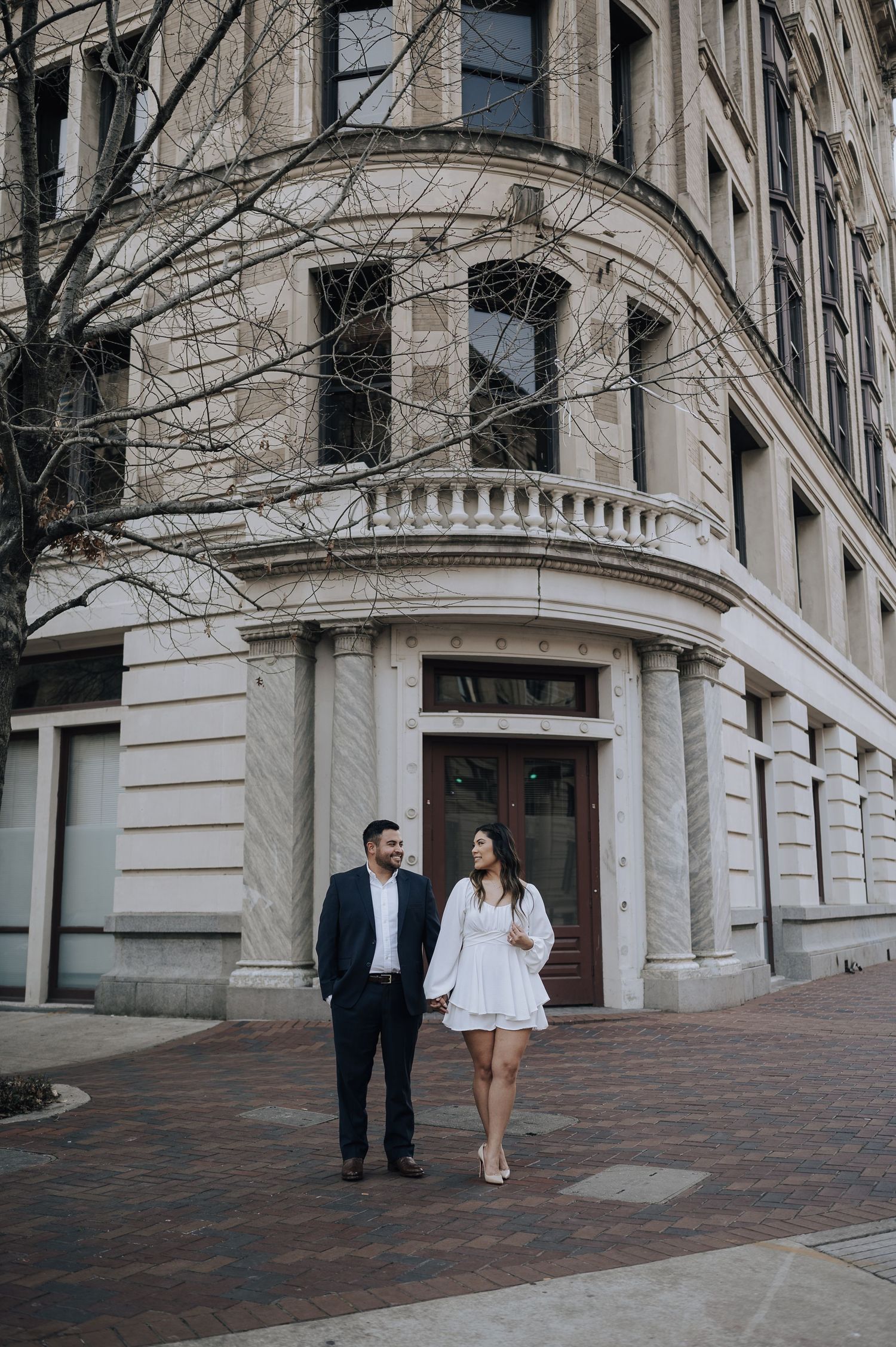 Houston area couple's engagement session. They are holding hands and walking across Franklin Street in downtown.