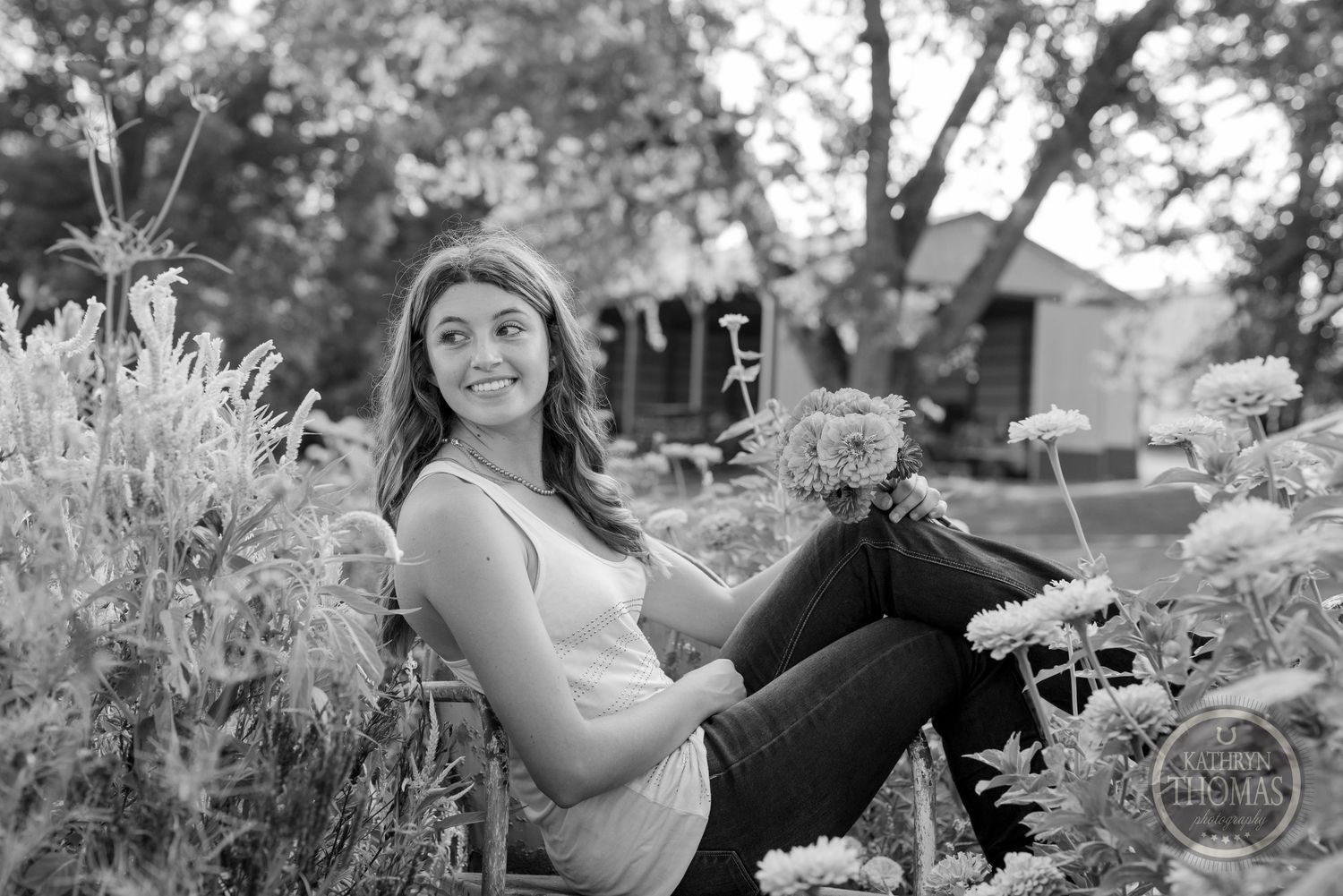 Black and white portrait of person in garden setting with flowers.