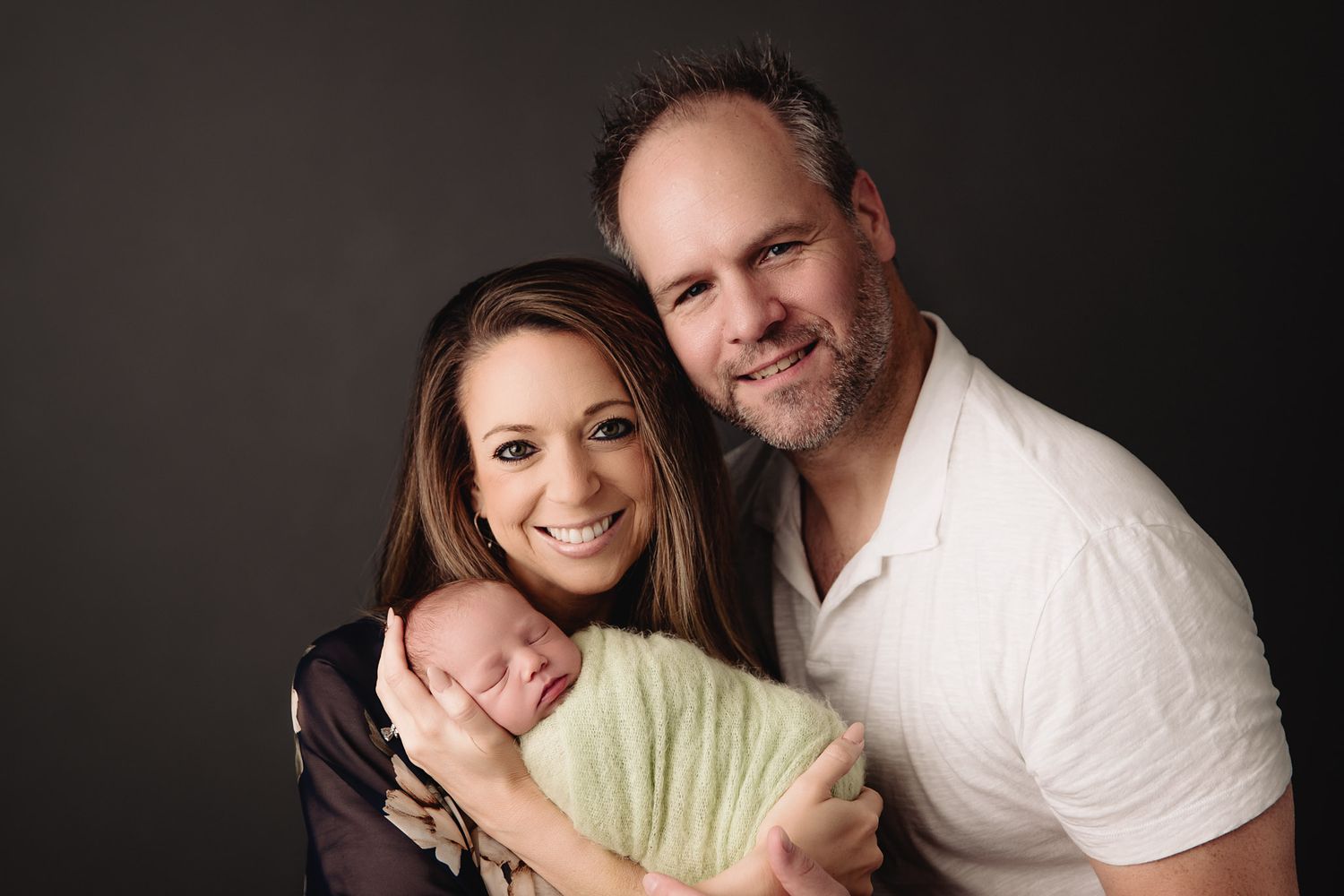 mother and father posed holding sleeping baby