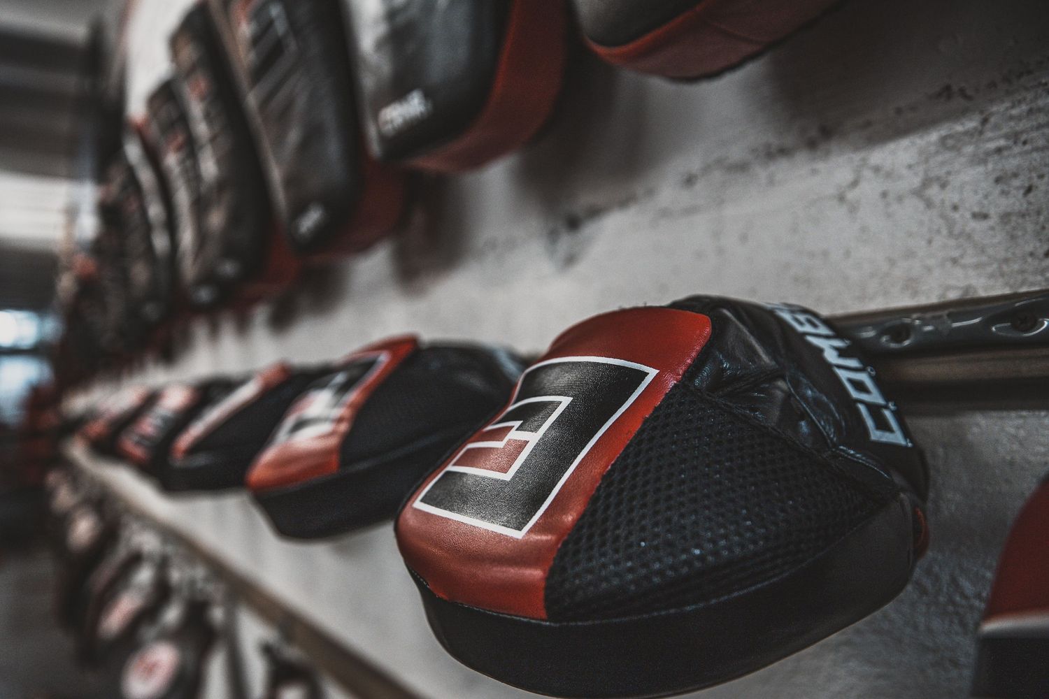 Row of red and black boxing gloves lined up against dark background.