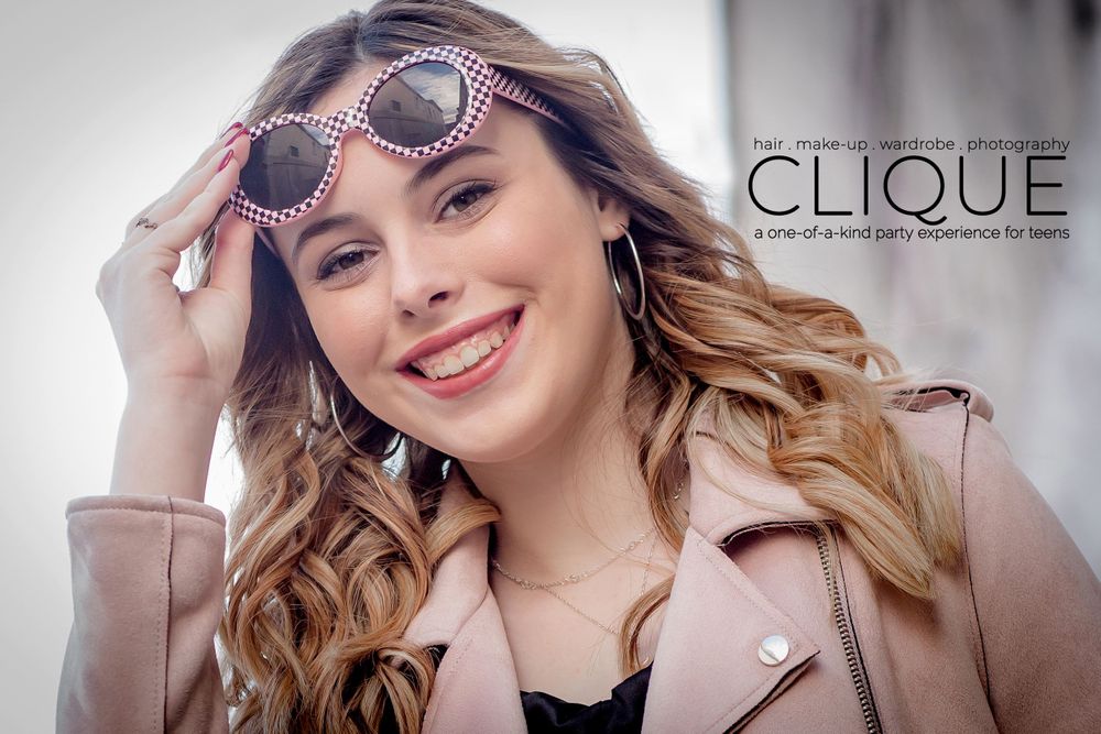 Fashion portrait of woman lifting sunglasses with studio branding overlay.