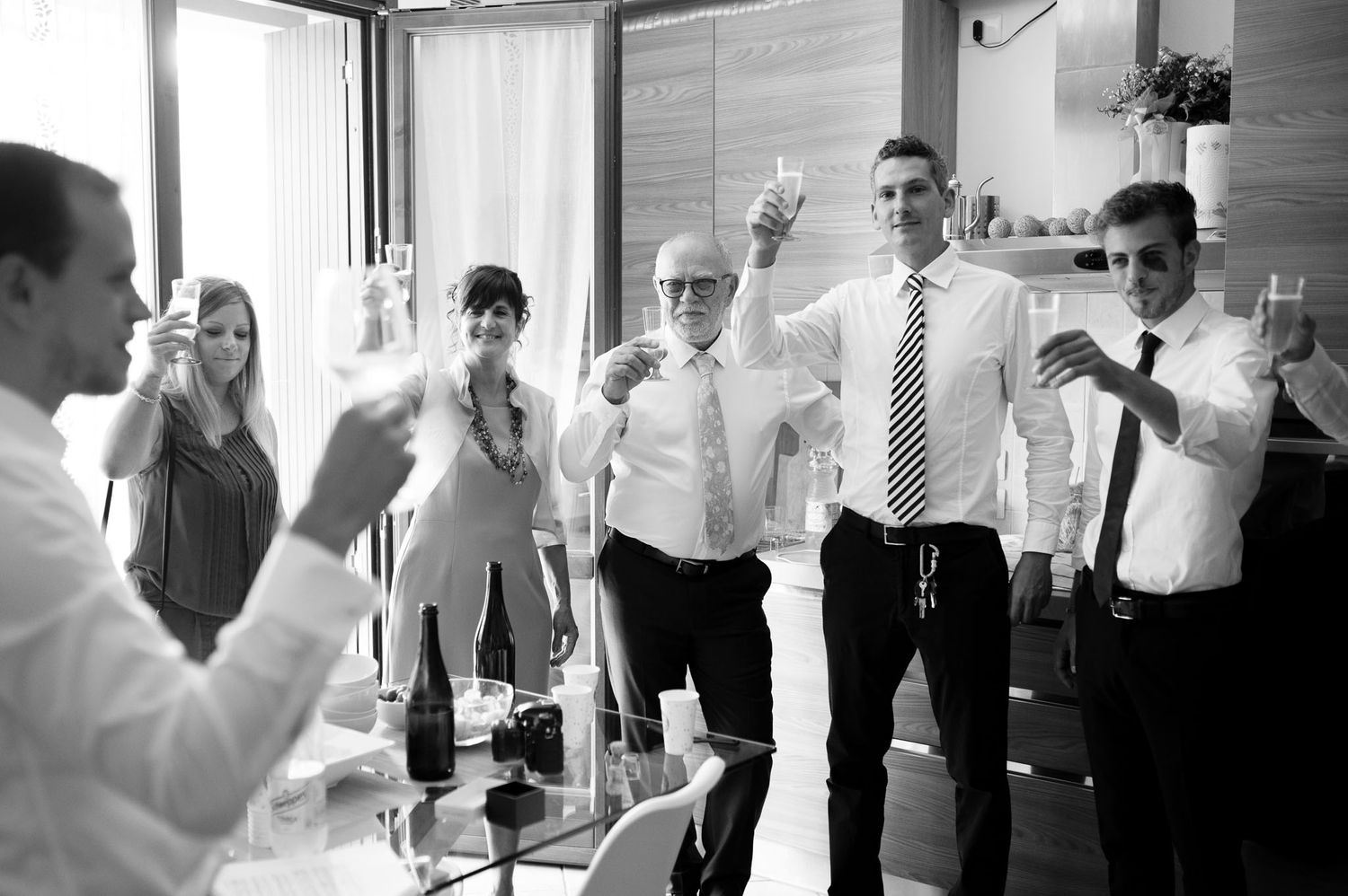 Black and white photo of wedding guests raising glasses in a celebratory toast.