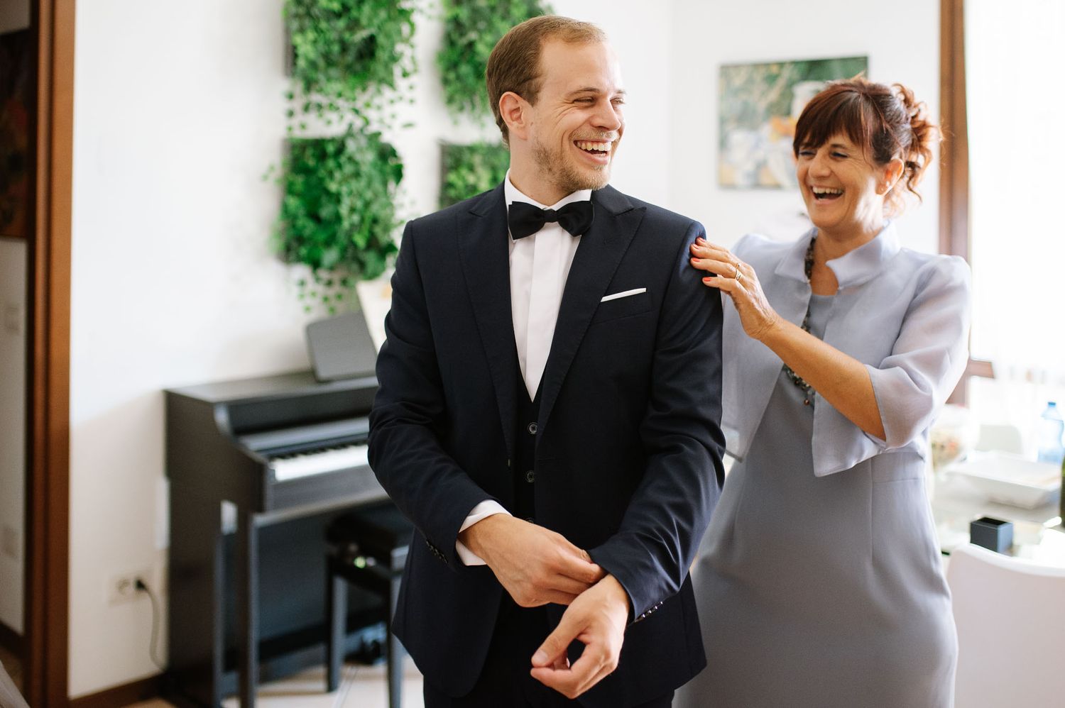 Couple sharing a lighthearted moment while getting dressed for formal occasion.