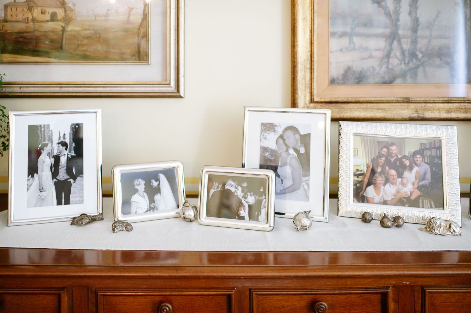 Collection of framed family photos displayed on wooden sideboard.