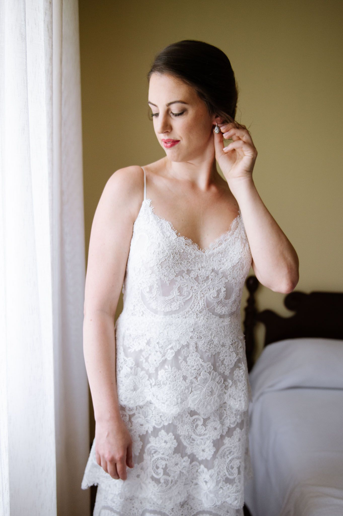 Elegant bridal portrait with lace wedding dress near a bright window.