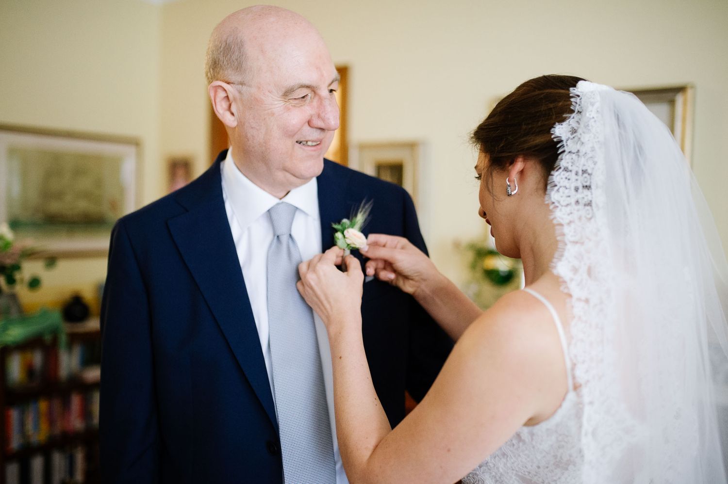 A heartfelt moment during a wedding ceremony as a boutonniere is pinned on a navy suit.