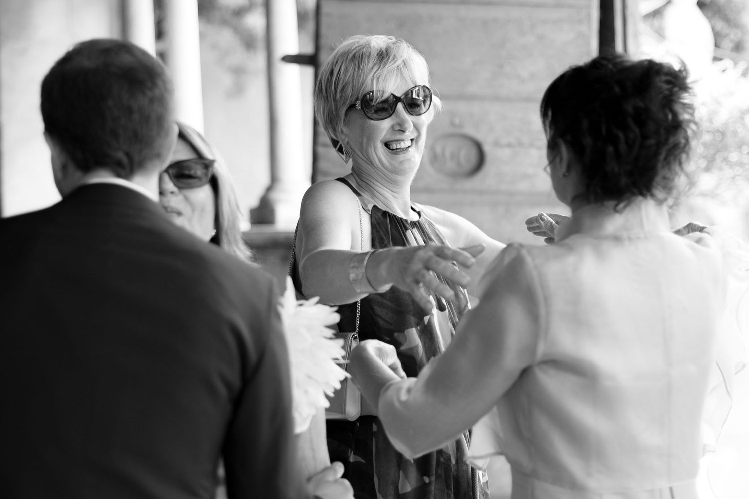 Candid black and white photo captures joyful laughter during wedding reception.