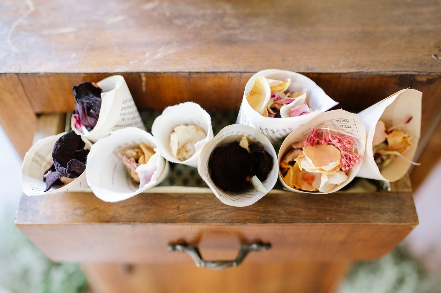 Wooden tray displays assorted wedding favors and treats in paper cones.