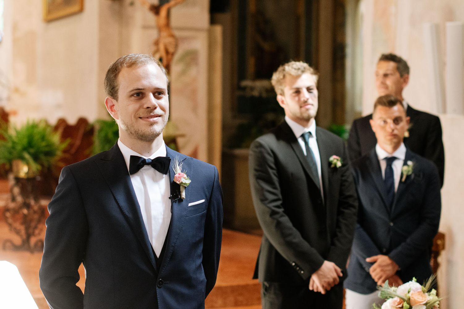 Wedding party members standing at altar in formal attire.