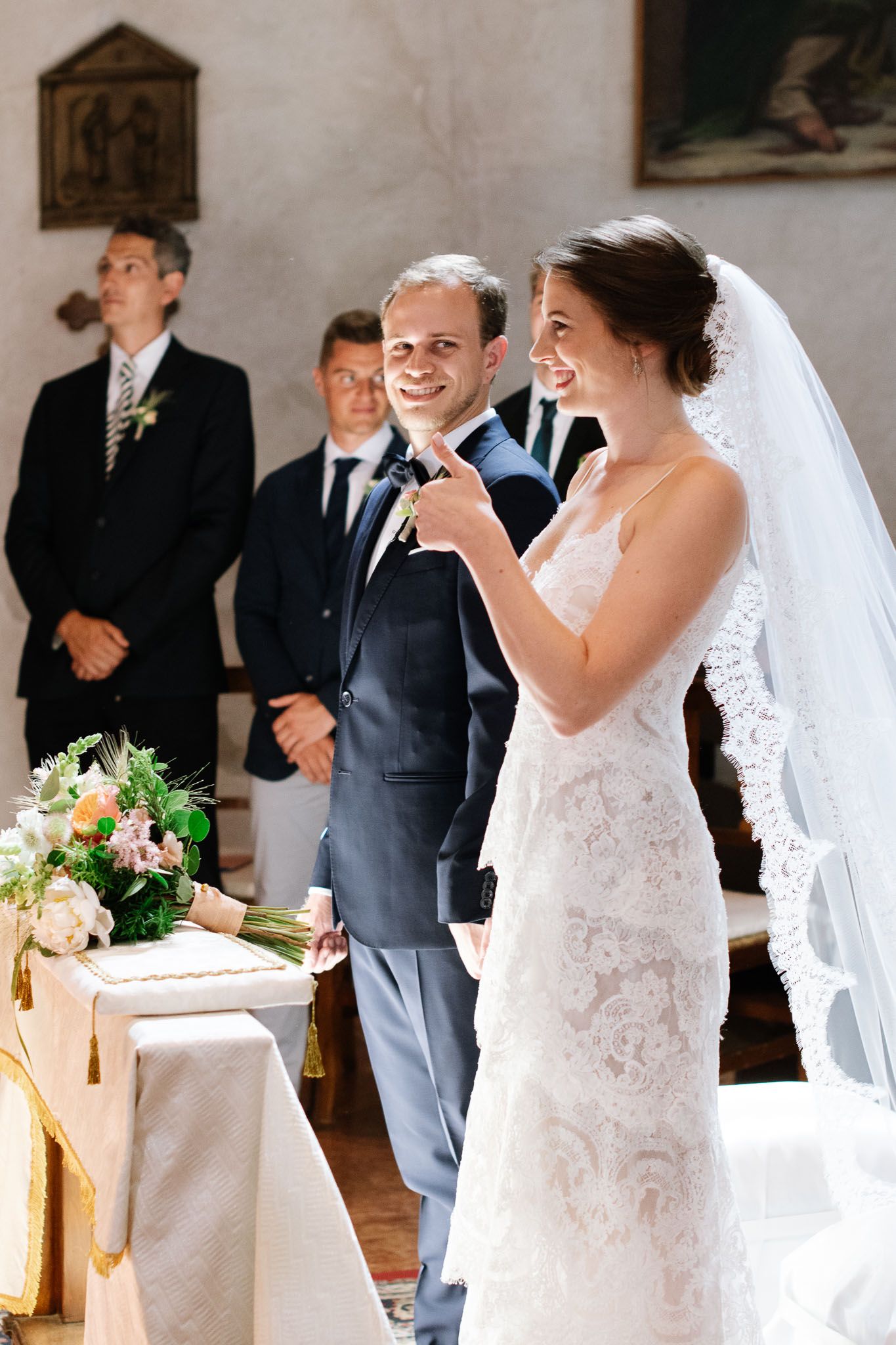 Wedding ceremony participants at decorated altar in historic church.