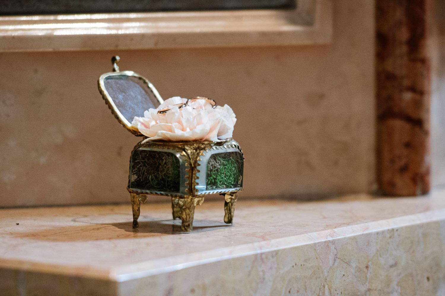 Decorative vintage jewelry box with pearls sitting on stone ledge.