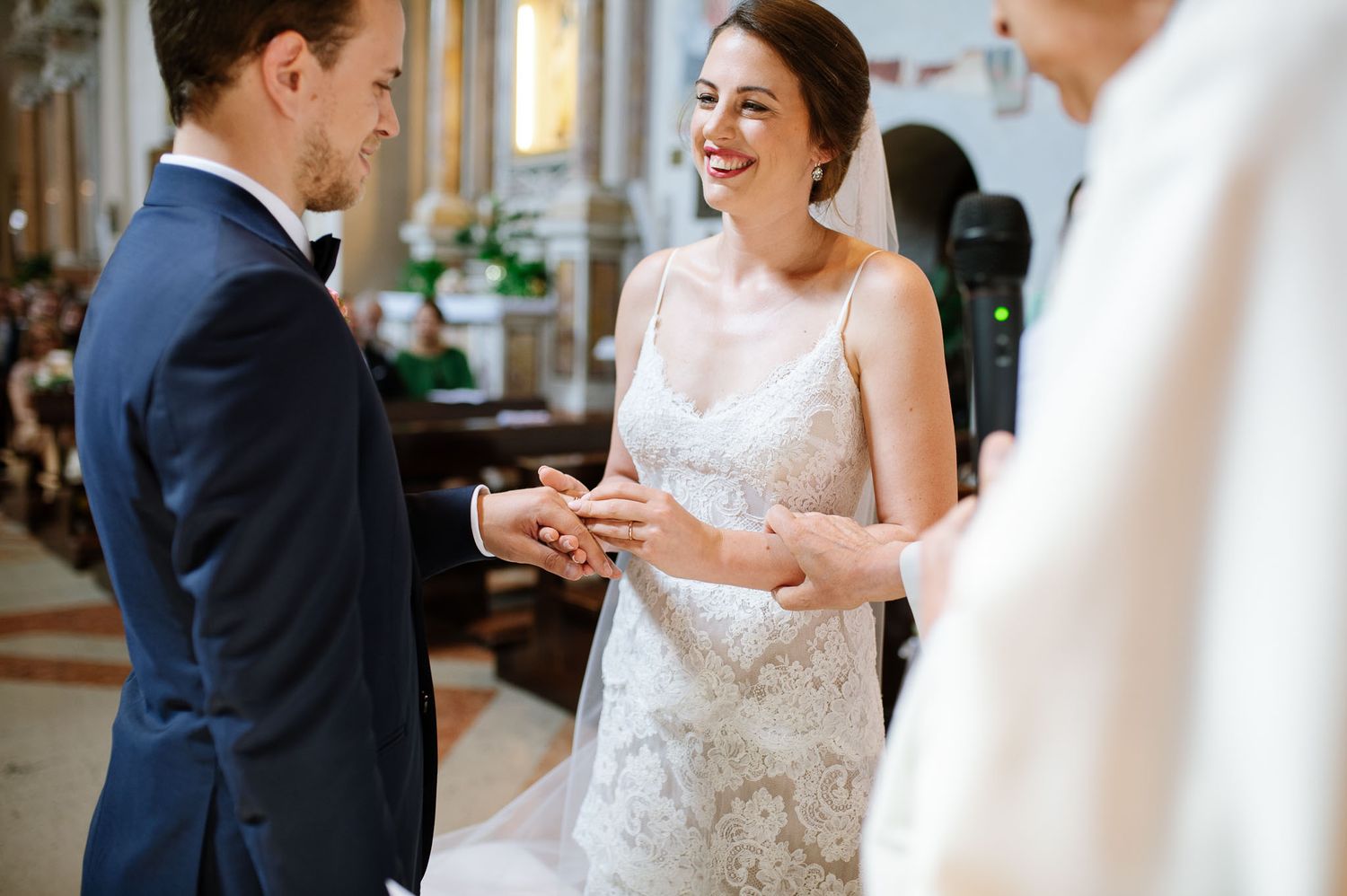 A couple exchanges rings during their wedding ceremony in a beautiful church setting.