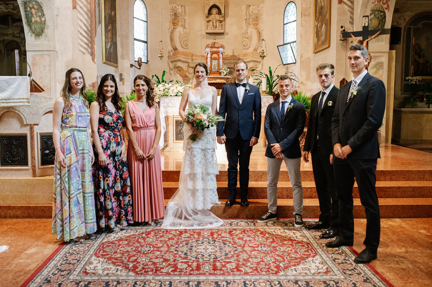 Wedding party poses for formal group photo in an ornate church sanctuary.