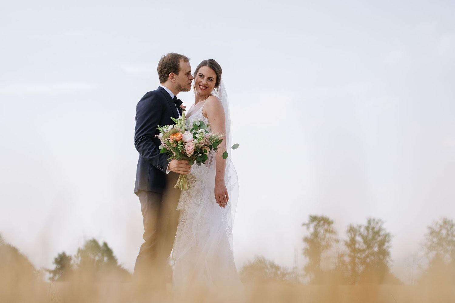An intimate wedding portrait taken in a wheat field during golden hour.