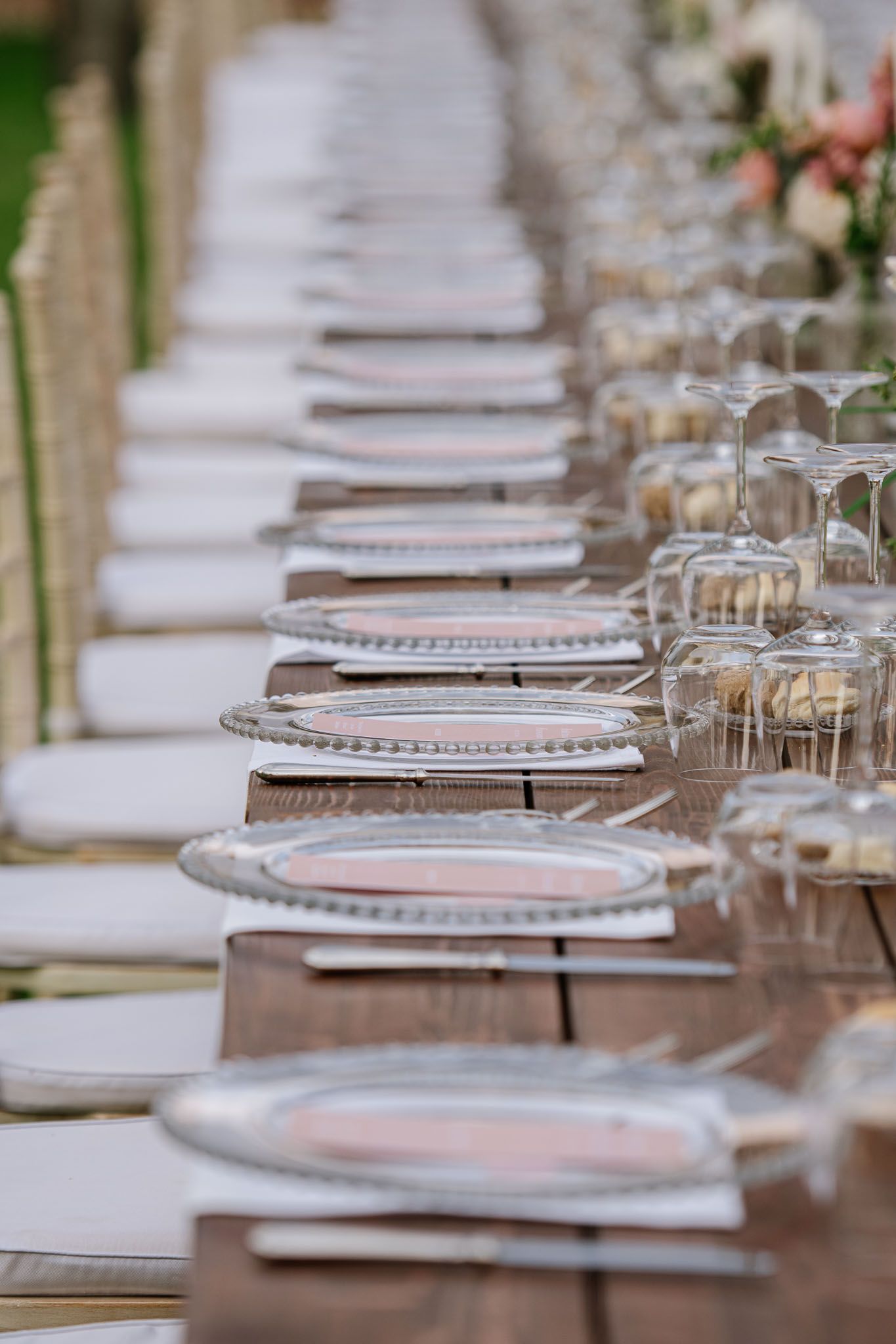 An elegant place setting with crystal glassware and silver charger plates at a wedding reception.