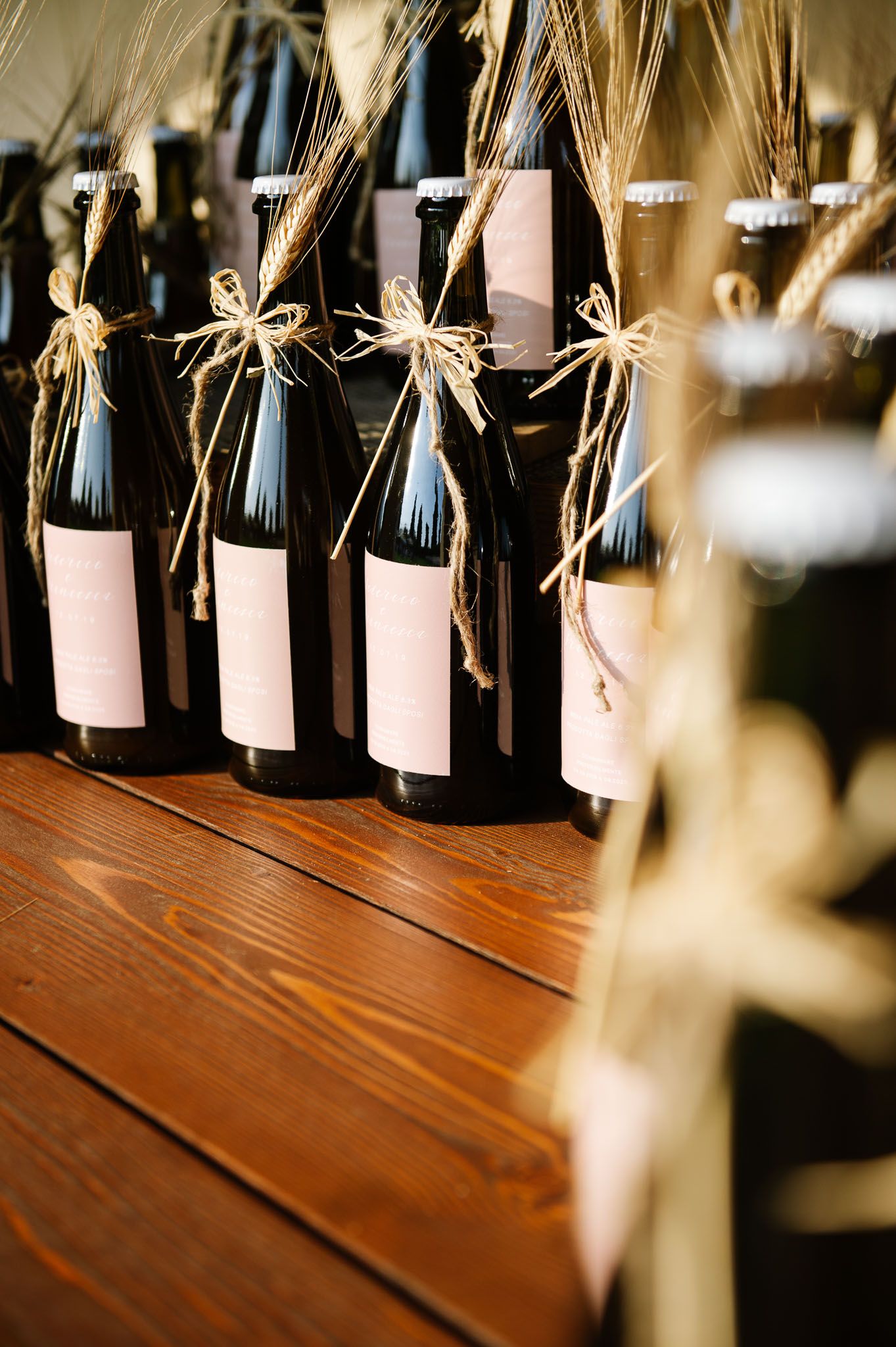 Wine bottles decorated with twine bows displayed on wooden surface during wedding celebration.