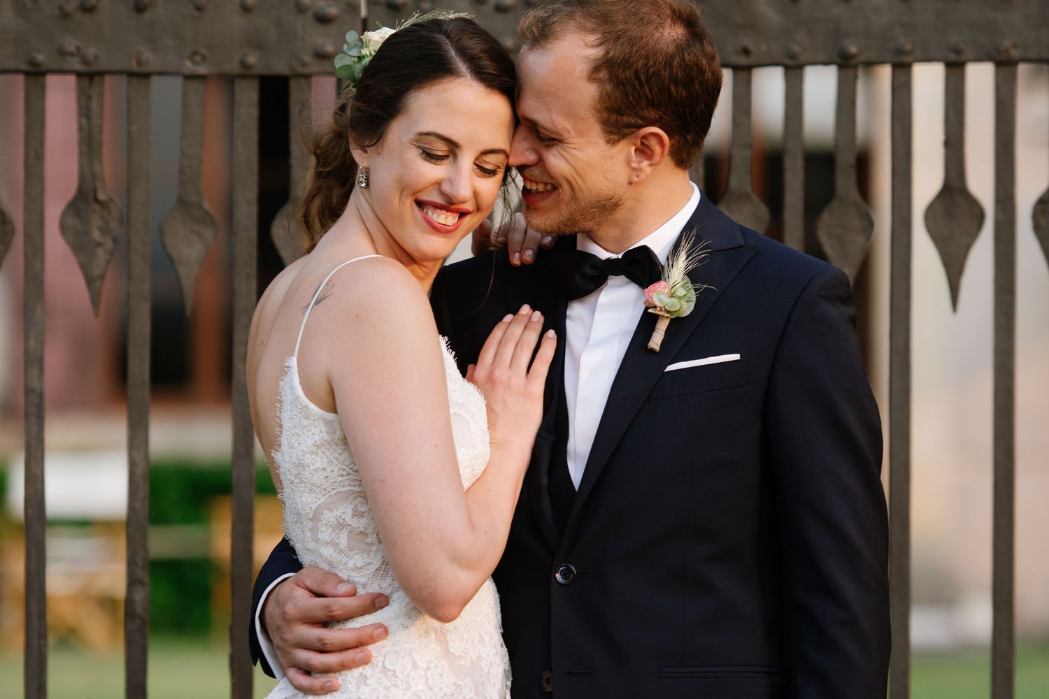 Intimate moment between newlyweds against an ornate iron gate background.