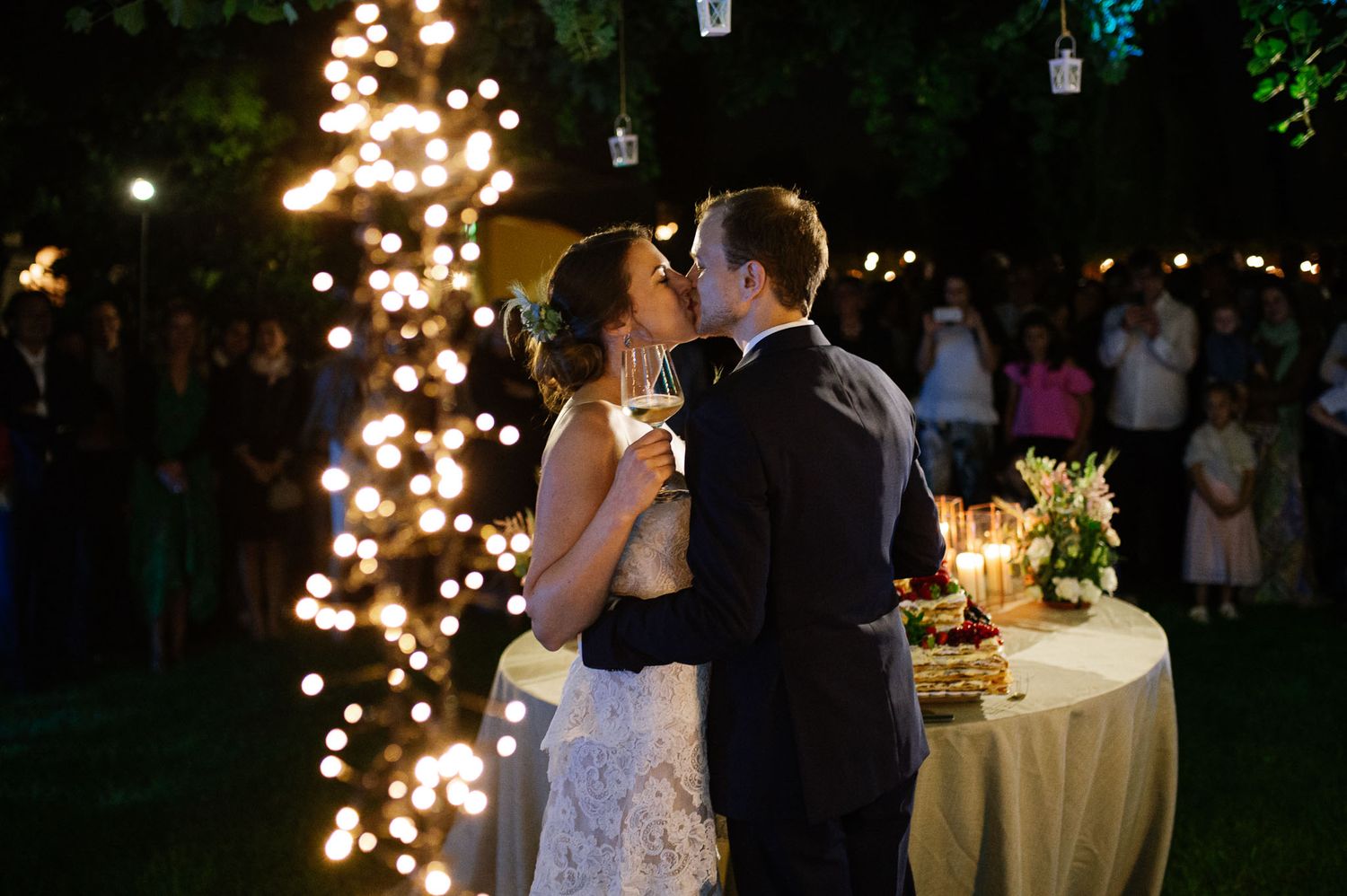 An intimate evening wedding reception moment captured with twinkling lights and elegant table settings.