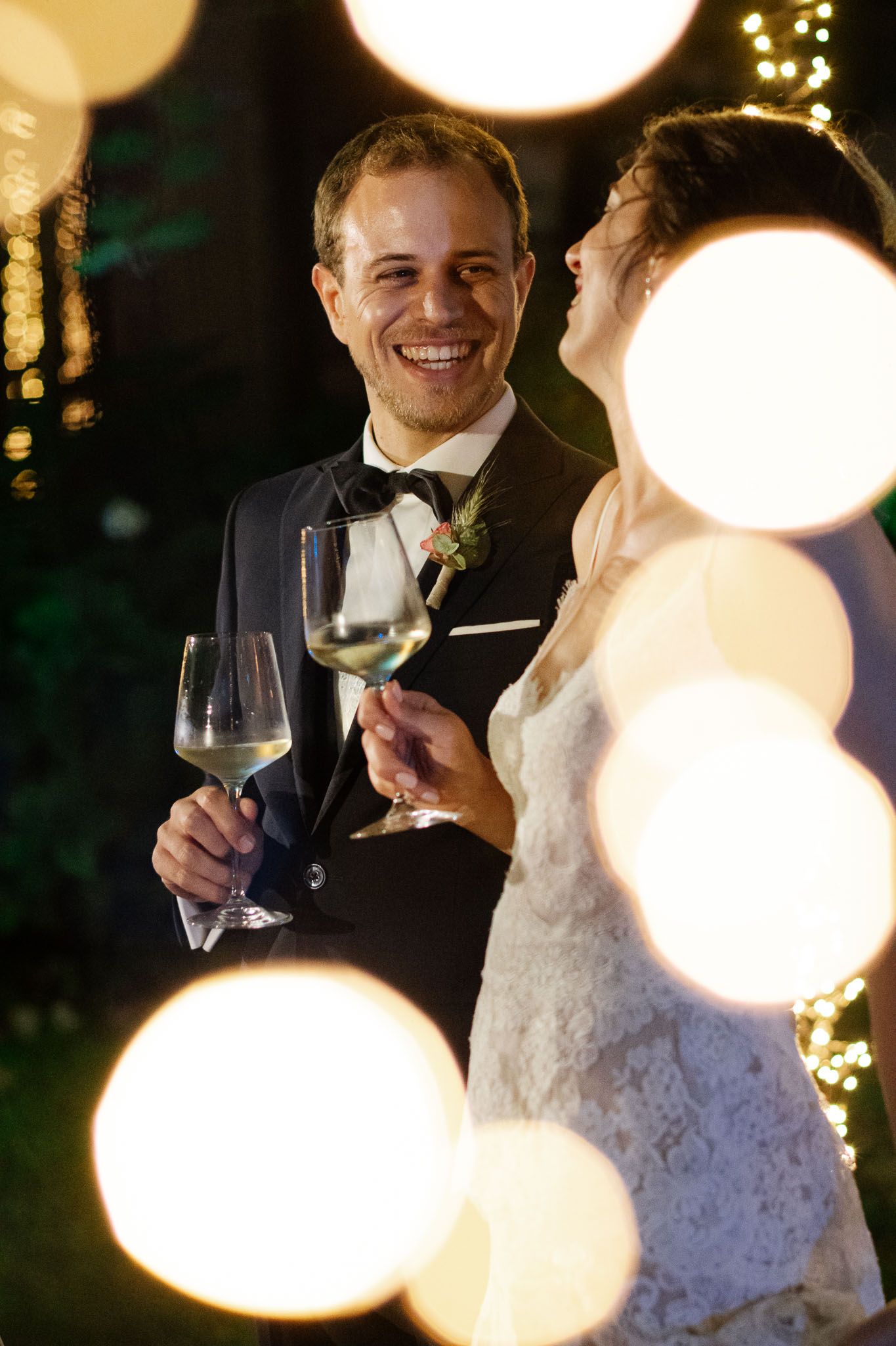 Joyful wedding reception moment with champagne glasses and beautiful bokeh lighting effects.