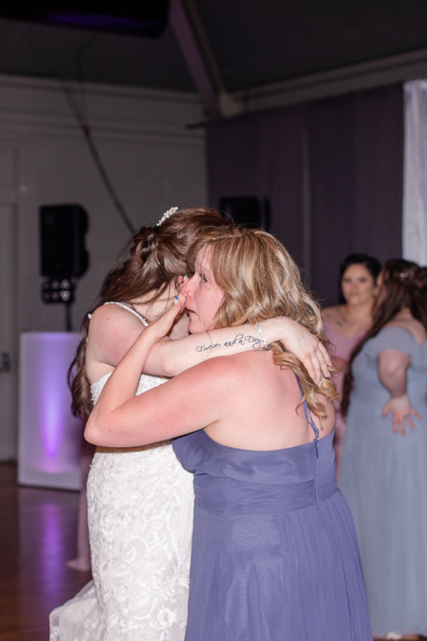 Tender moment shared between bride and bridesmaid during wedding reception celebrations.