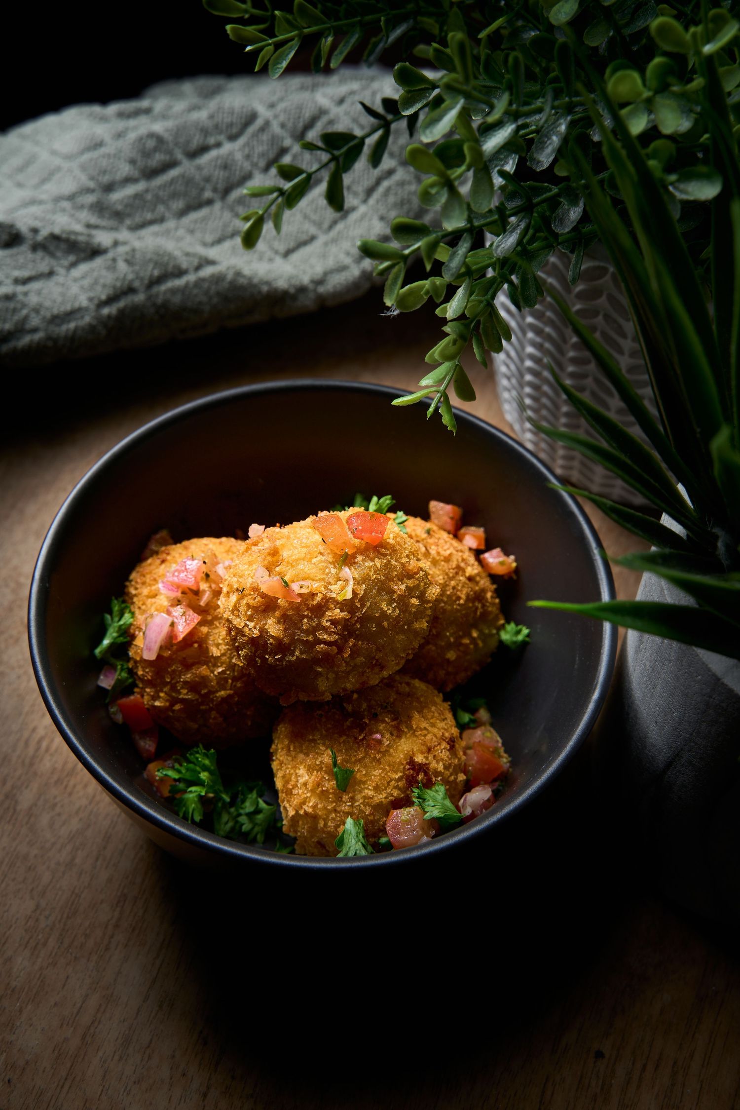 Crispy breaded fish fillet served with herbs in a black bowl.