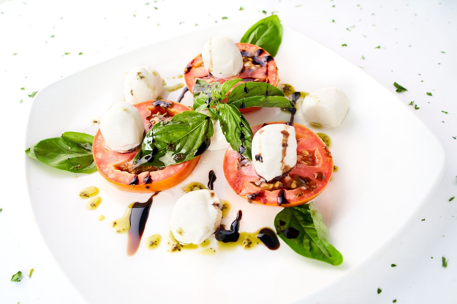 Fresh caprese salad with mozzarella, tomatoes, and basil drizzled with balsamic glaze.