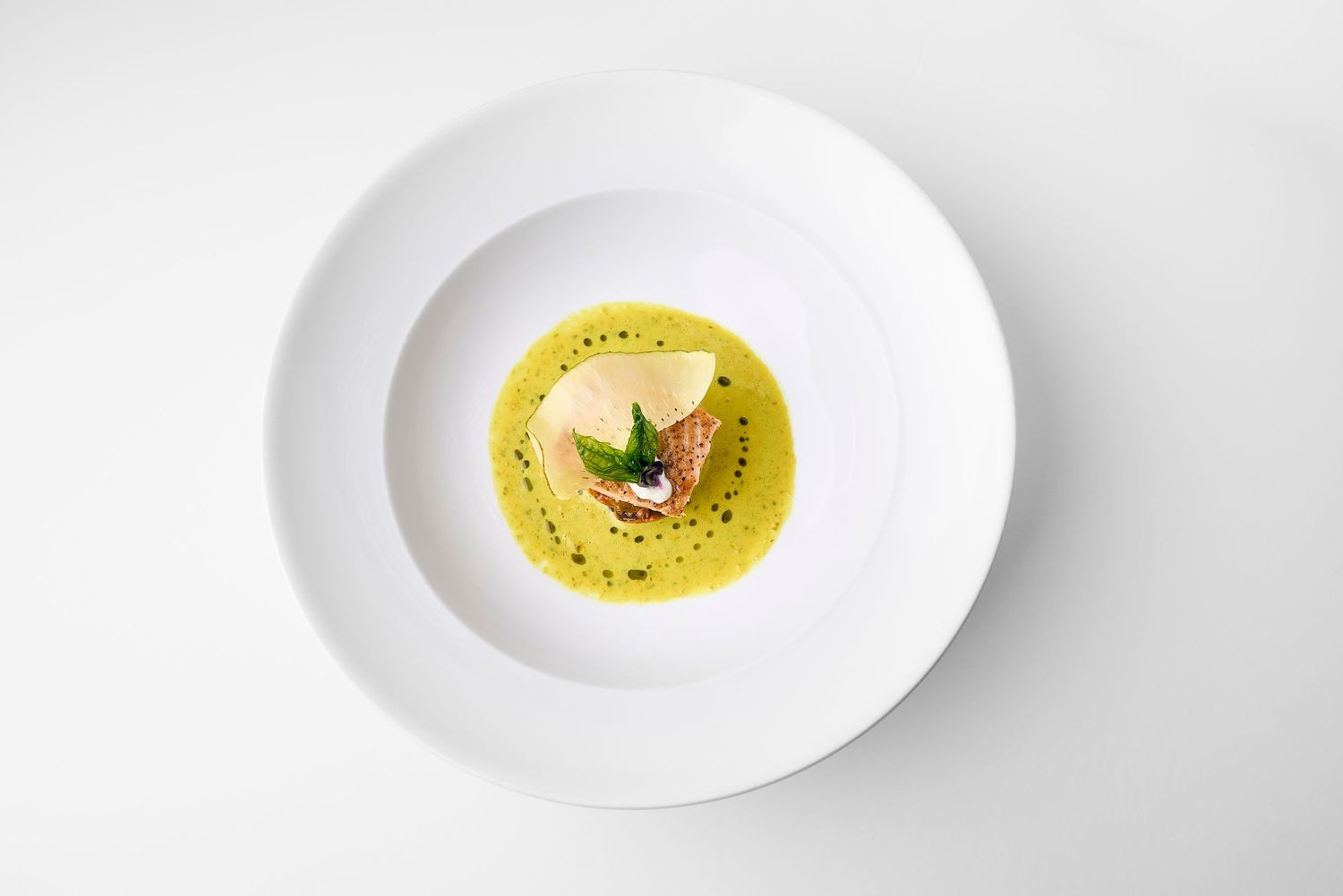 Series of white plates with yellow sauce or custard in minimalist presentation.
