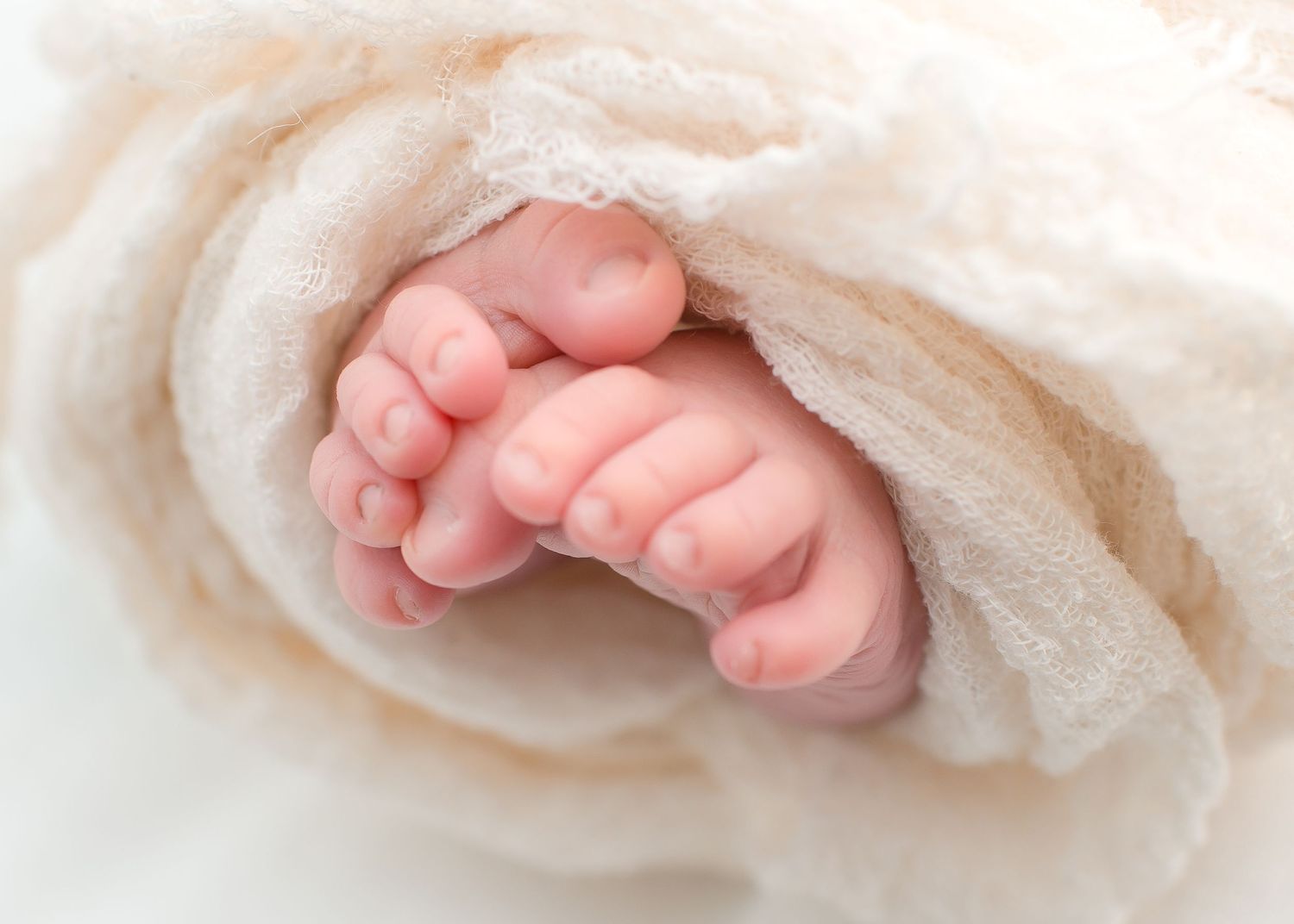 close up of newborn baby feet wrapped in a linen wrap for a natural light studio in houston texas