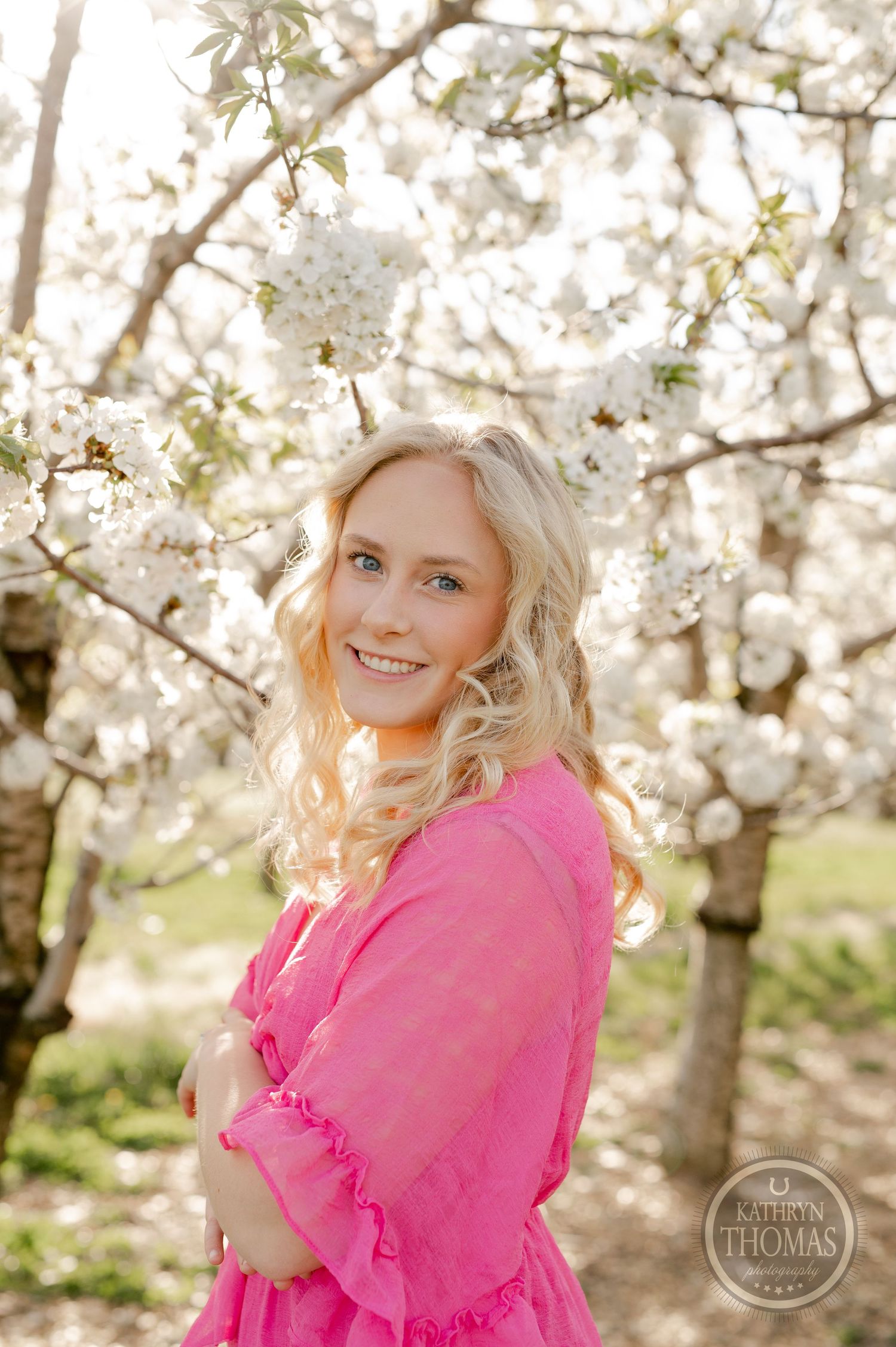 Portrait in a pink dress surrounded by delicate white cherry blossoms.