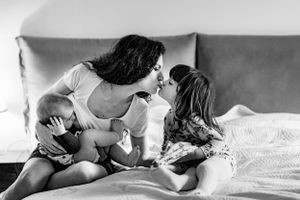 Mother nurses her infant daughter while kissing her oldest during a family photoshoot in The Hague.