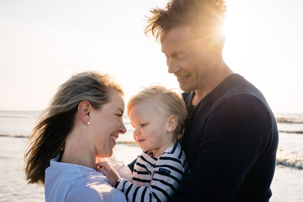 Mother and father hug their sun during sunset on a beach in The Hague.