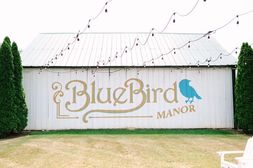 White fence with string lights and elegant gold manor signage.