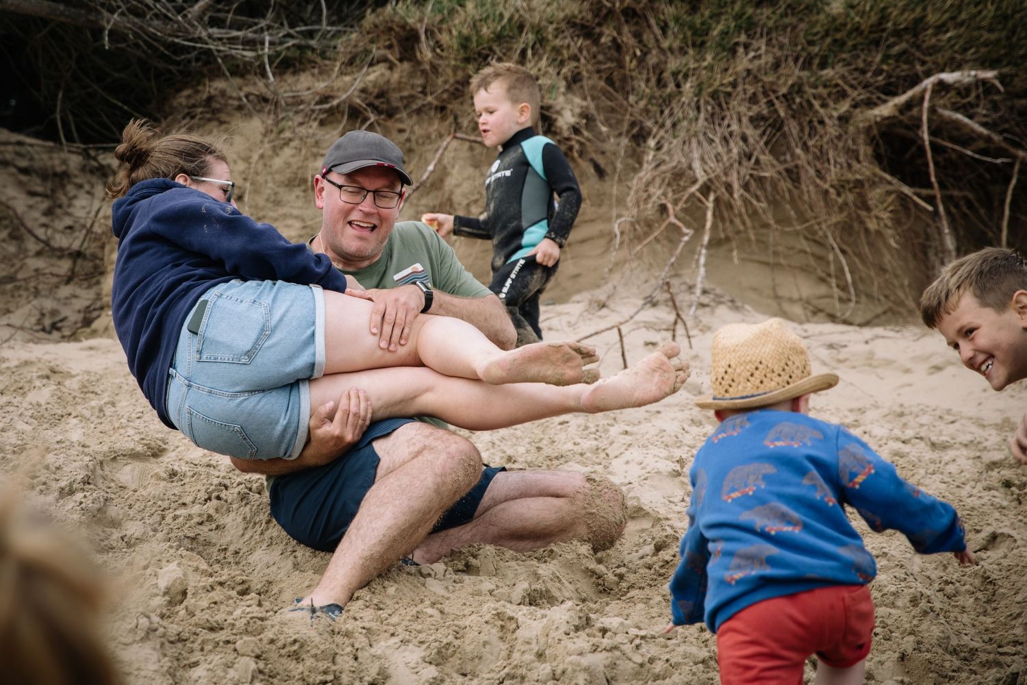 Candid moment of family playtime on sandy slopes during outdoor adventure.