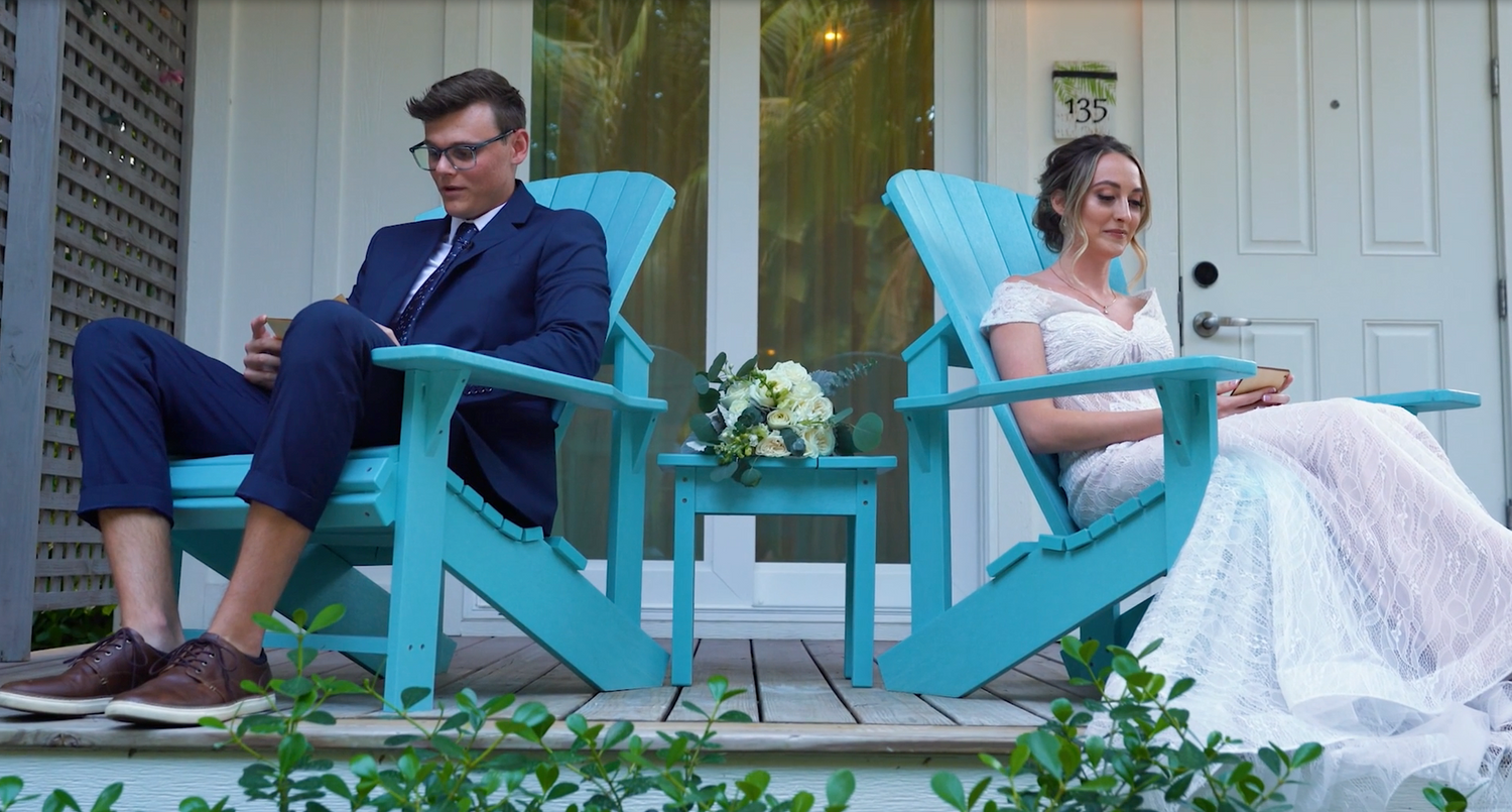 Wedding party relaxing on a blue porch with white railings at a beach house.