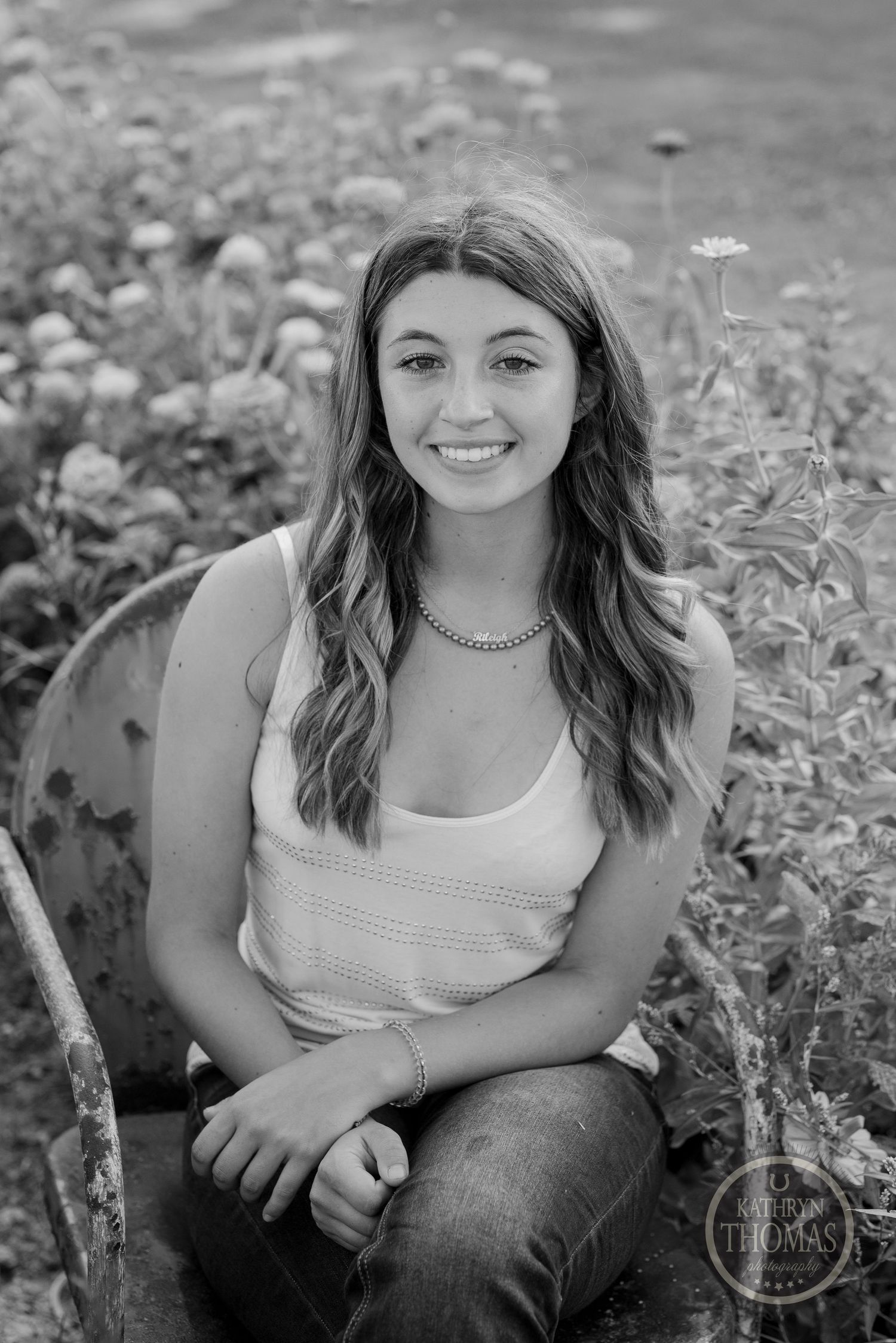 A black and white portrait of a person surrounded by delicate garden flowers.