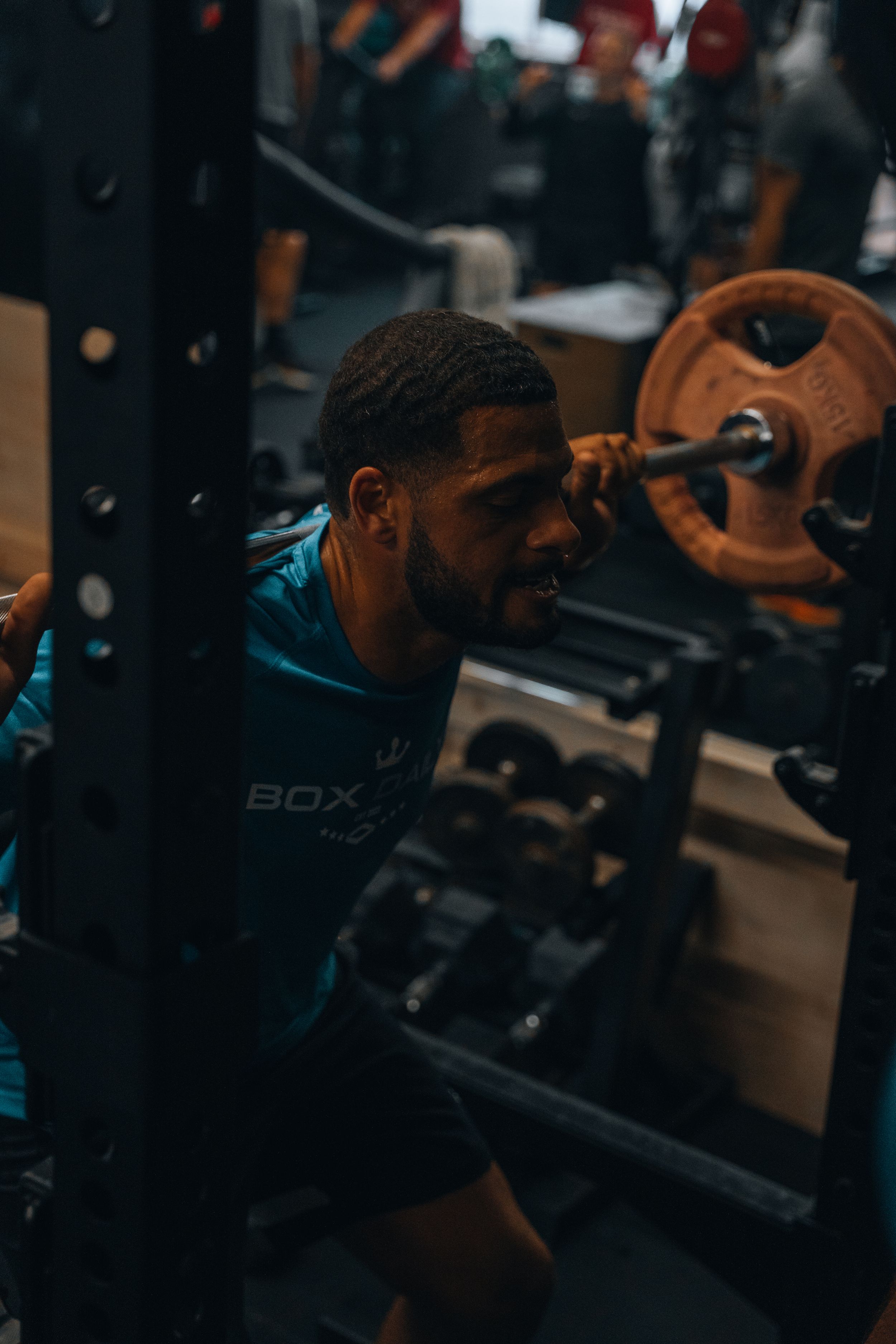 Fitness enthusiast training near weight equipment in dimly lit gym setting.