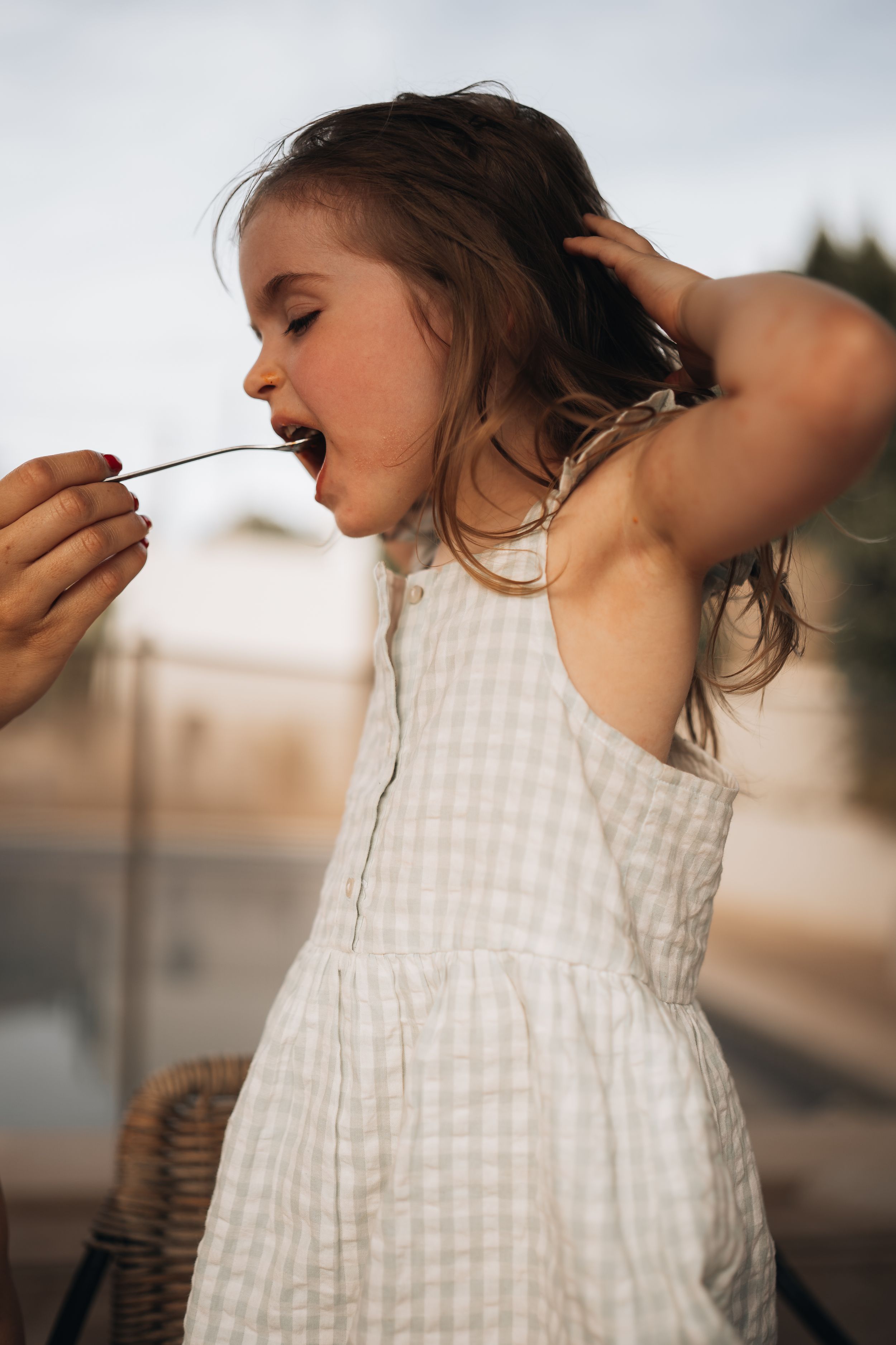 Series of close-up shots showing a child in a checkered dress playing with their hair.