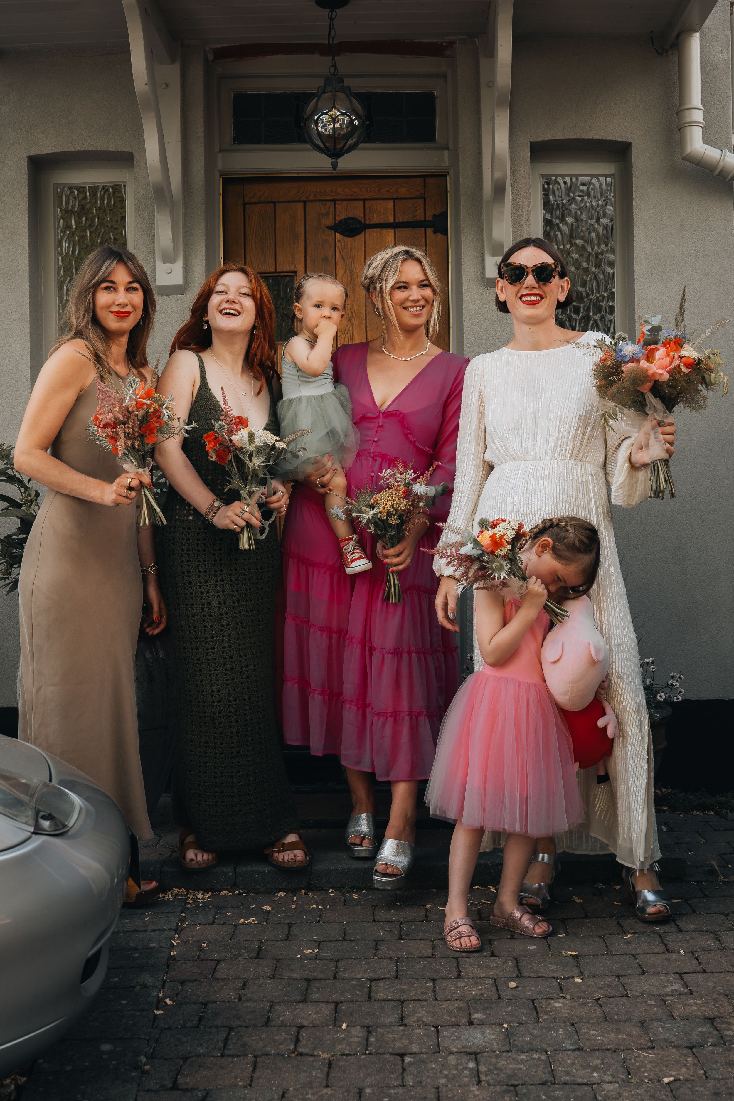 Candid shot of wedding party laughing together while holding colorful bouquets.