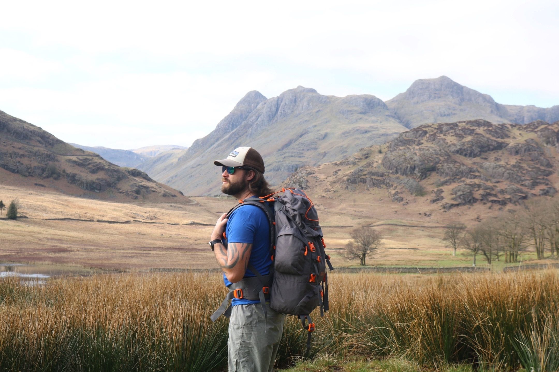 Hiker with backpack admiring rugged mountain scenery in remote wilderness.